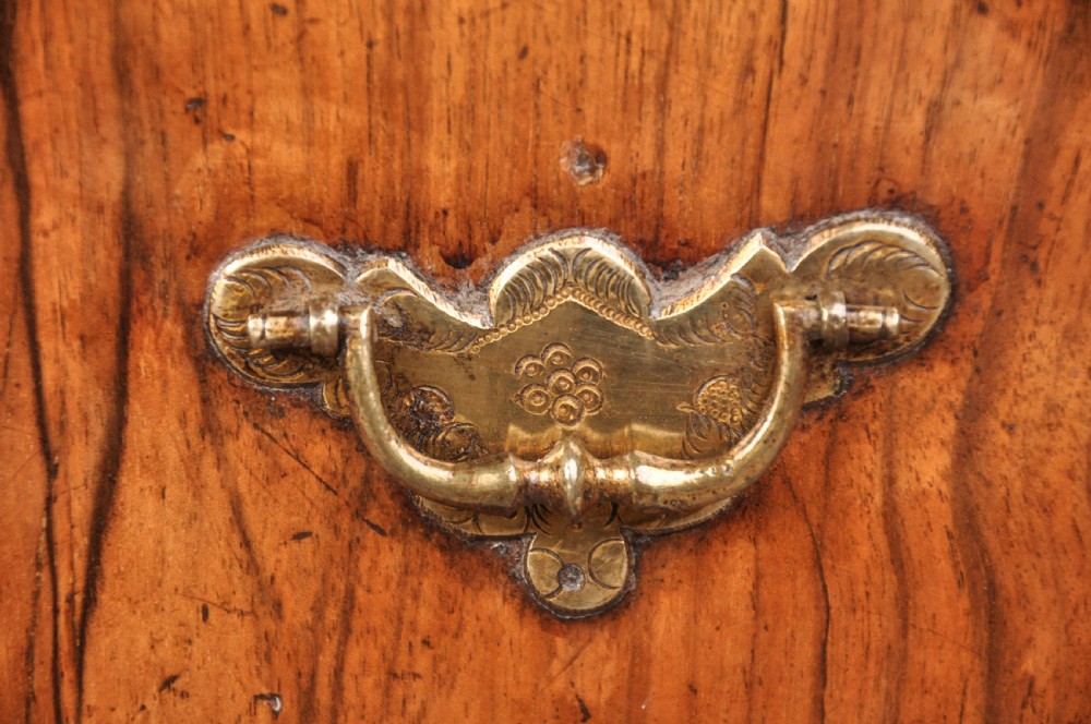 An early eighteenth century walnut bachelor chest featuring a fold-over top, four graduated drawers with brass handles, and bracket feet. View IV