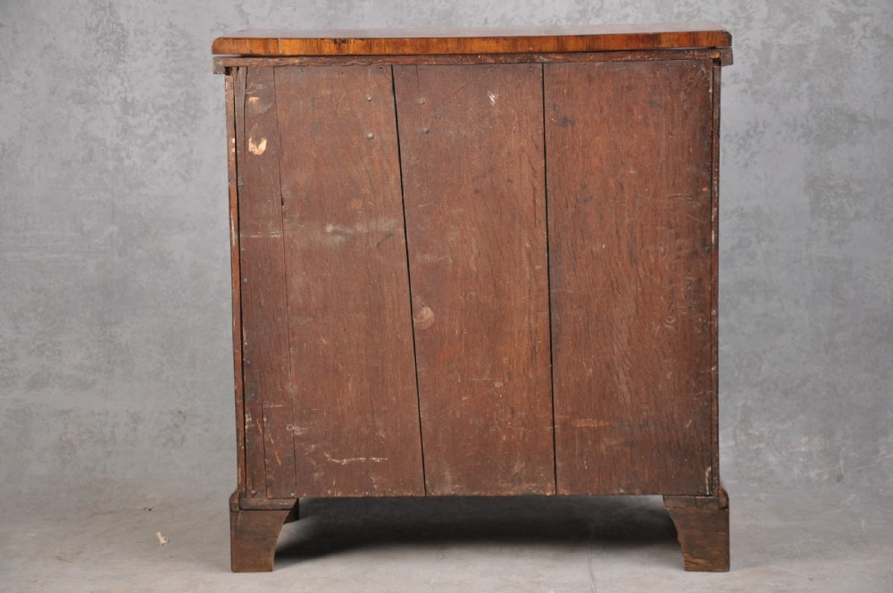 An early eighteenth century walnut bachelor chest featuring a fold-over top, four graduated drawers with brass handles, and bracket feet. View IX