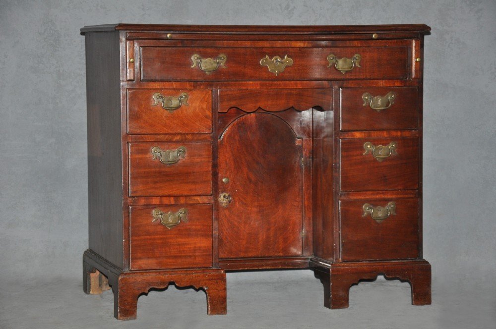 An 18th-century Georgian mahogany kneehole desk featuring six small drawers, one long top drawer, a central recessed cupboard, and brass handles on bracket feet.