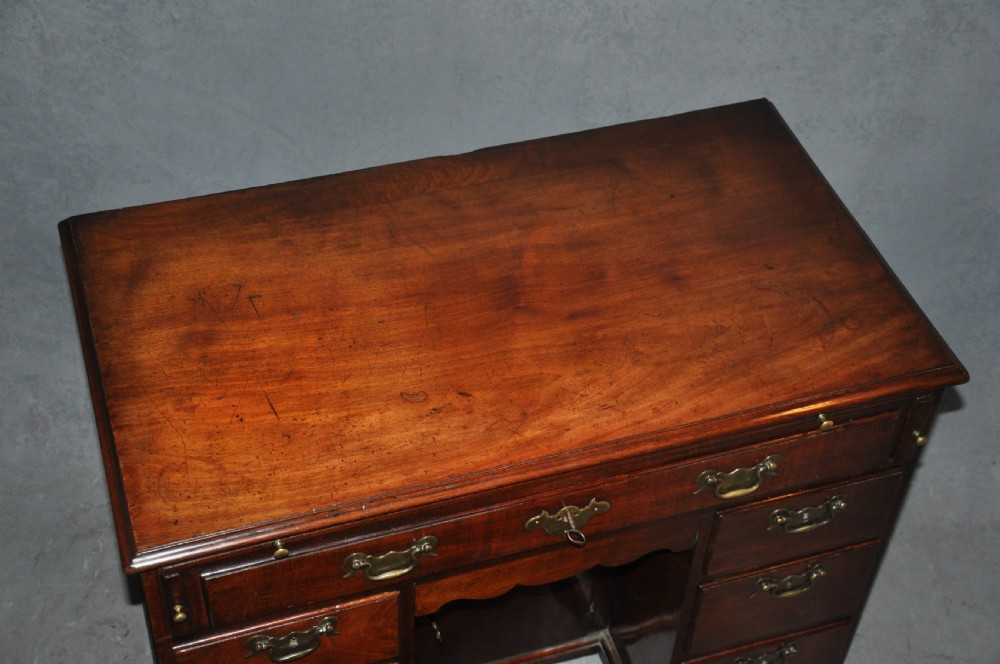 An 18th-century Georgian mahogany kneehole desk featuring six small drawers, one long top drawer, a central recessed cupboard, and brass handles on bracket feet. View II