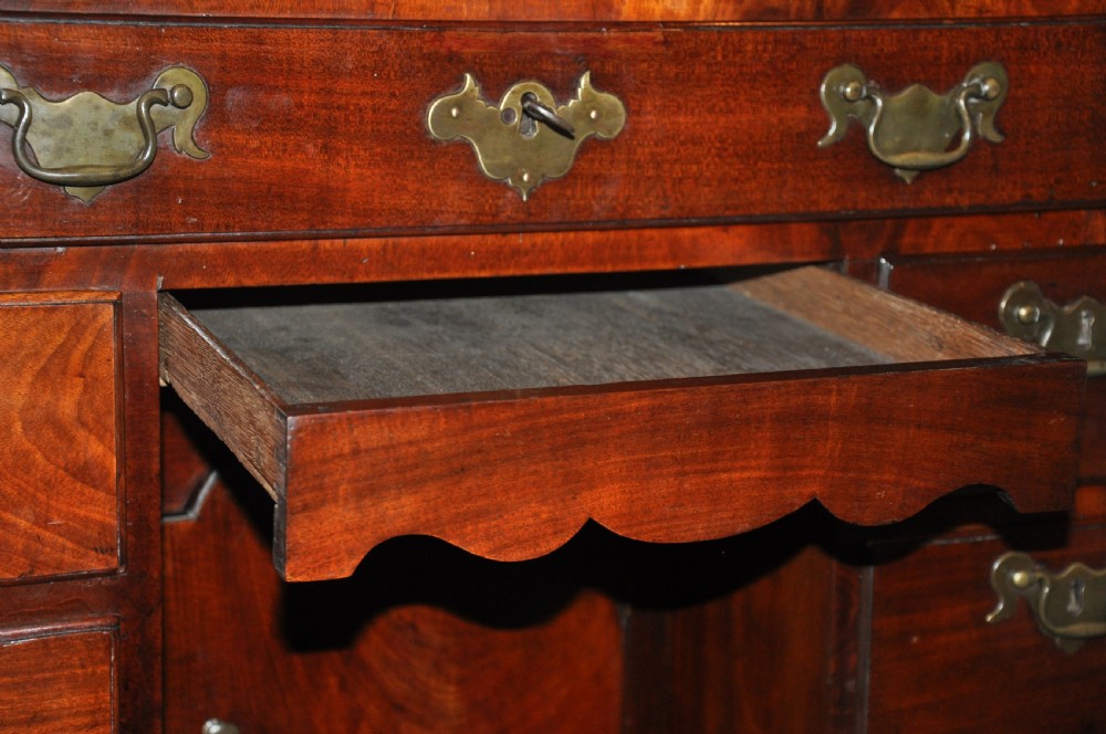 An 18th-century Georgian mahogany kneehole desk featuring six small drawers, one long top drawer, a central recessed cupboard, and brass handles on bracket feet. View VII