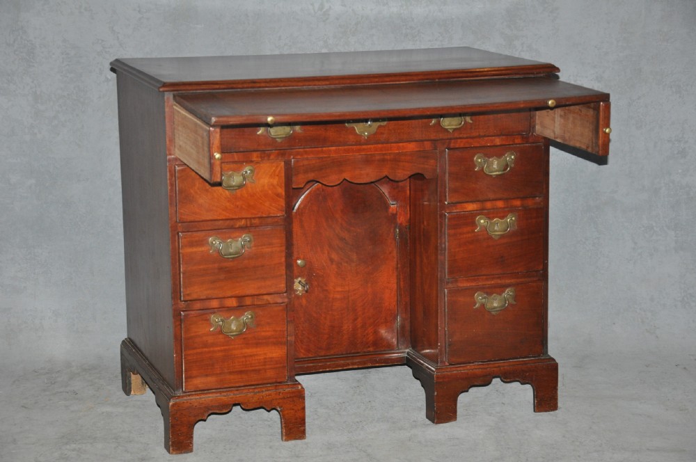 An 18th-century Georgian mahogany kneehole desk featuring six small drawers, one long top drawer, a central recessed cupboard, and brass handles on bracket feet. View XIII