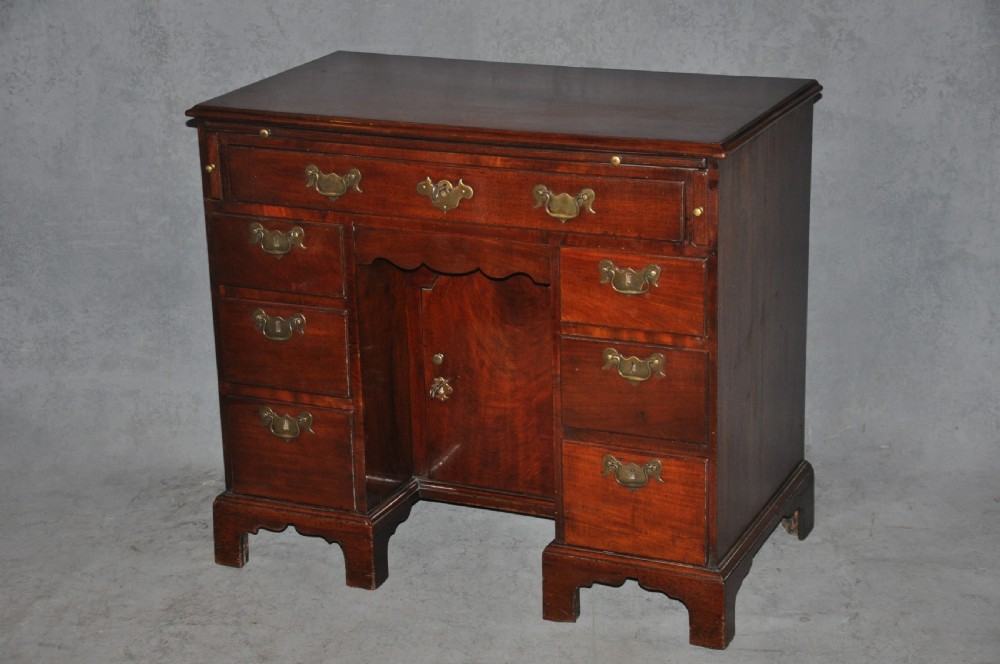 An 18th-century Georgian mahogany kneehole desk featuring six small drawers, one long top drawer, a central recessed cupboard, and brass handles on bracket feet. View XV