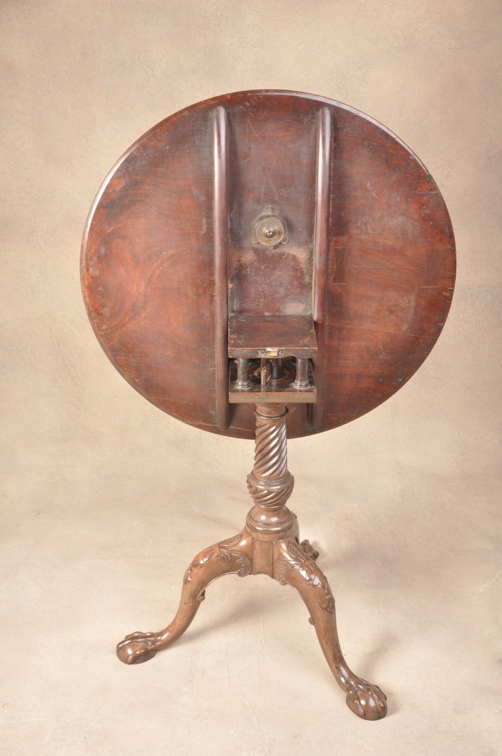 An 18th-century mahogany tilt-top tripod table shown with its circular surface locked vertically, revealing a spiral-carved pedestal and cabriole legs ending in claw and ball feet. View VII