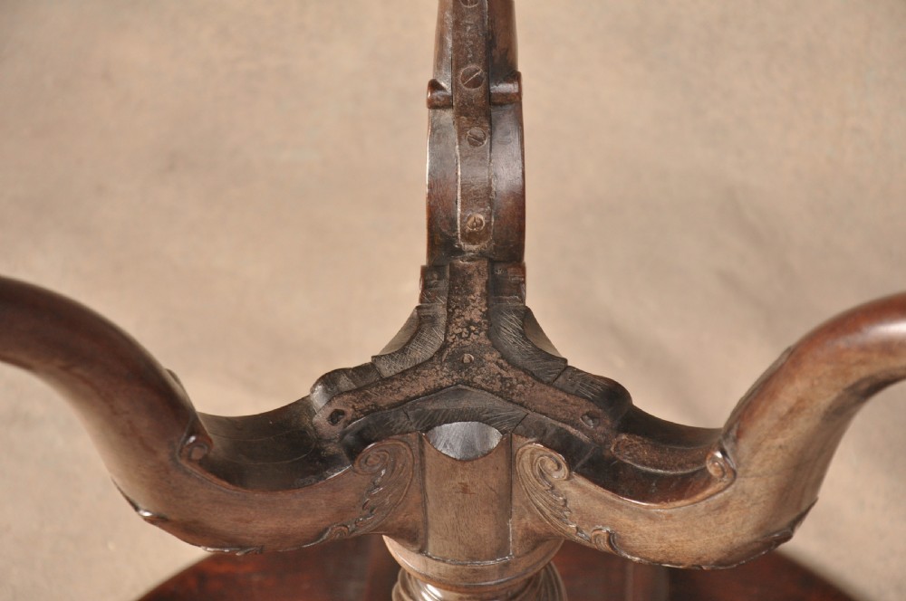 An 18th-century mahogany tilt-top tripod table shown with its circular surface locked vertically, revealing a spiral-carved pedestal and cabriole legs ending in claw and ball feet. View X