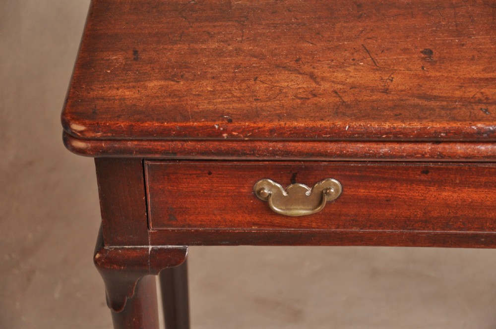 A mid-18th-century mahogany fold-over tea table featuring a single frieze drawer with brass handles and slender cabriole legs ending in pad feet. View X