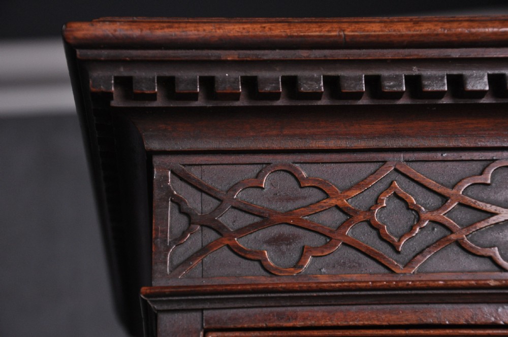 An 18th-century mahogany tallboy featuring two sections of graduated drawers, brass handles, carved blind fretwork frieze, and ogee bracket feet. View IV