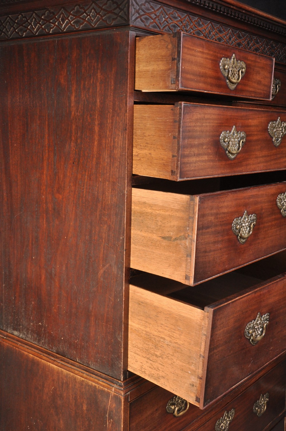 An 18th-century mahogany tallboy featuring two sections of graduated drawers, brass handles, carved blind fretwork frieze, and ogee bracket feet. View V