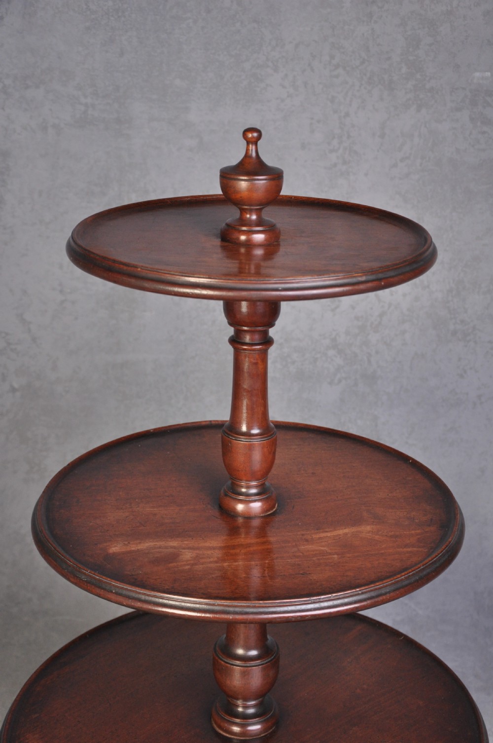 An 18th-century dark mahogany dumb waiter featuring three graduated circular dish trays supported by a turned central column on tripod cabriole legs. View V