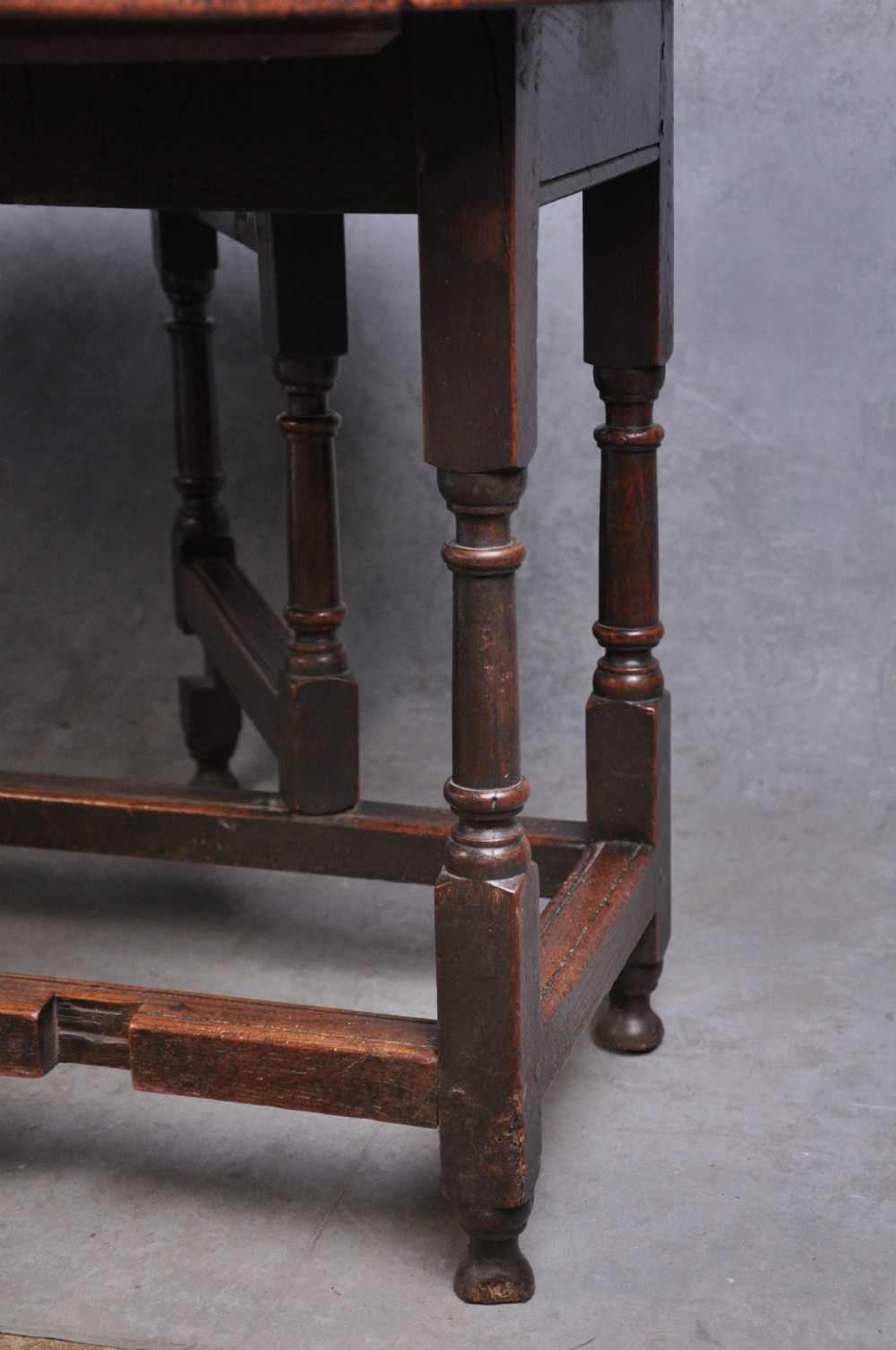 A seventeenth-century oak gateleg table shown with drop leaves folded down, featuring turned legs and low box stretchers. View VII