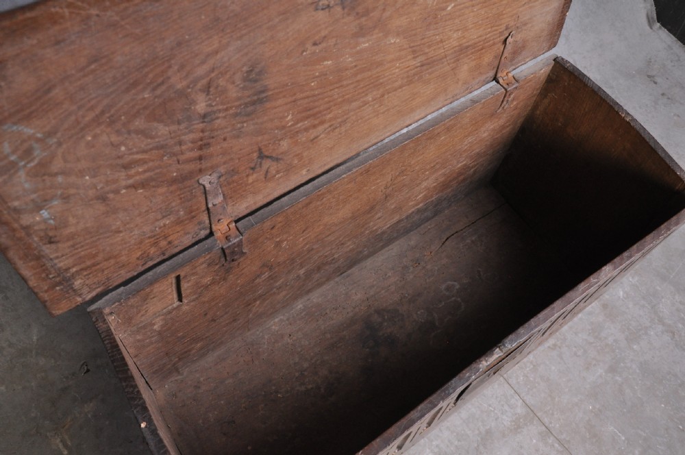 A dark carved oak plank coffer featuring twin carved diamond lozenges, a carved arched top frieze, and a central iron lockplate. View IV