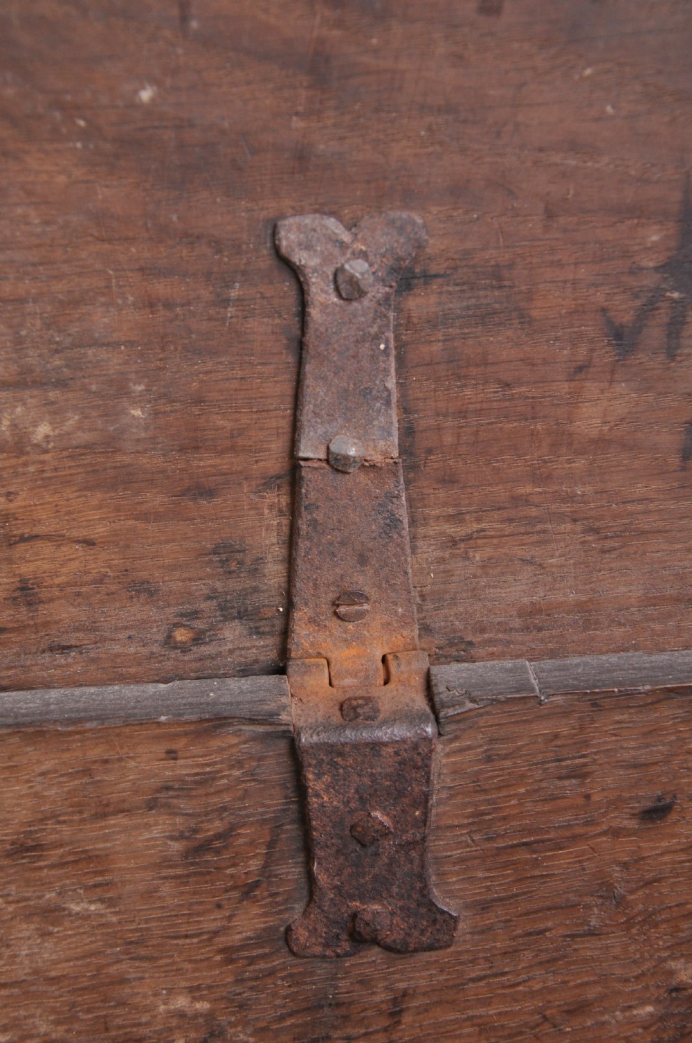 A dark carved oak plank coffer featuring twin carved diamond lozenges, a carved arched top frieze, and a central iron lockplate. View V