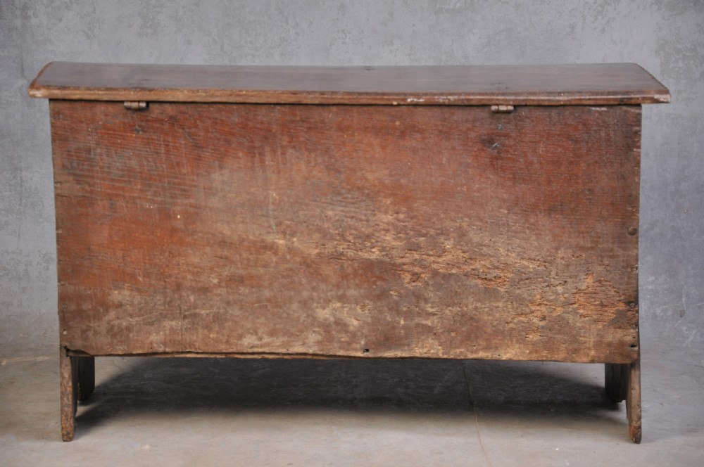 A dark carved oak plank coffer featuring twin carved diamond lozenges, a carved arched top frieze, and a central iron lockplate. View VII