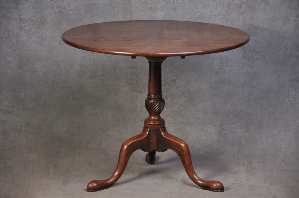 An 18th-century mahogany tripod table featuring a circular top resting on a turned column with a spiral carved knop and three cabriole legs terminating in pad feet.