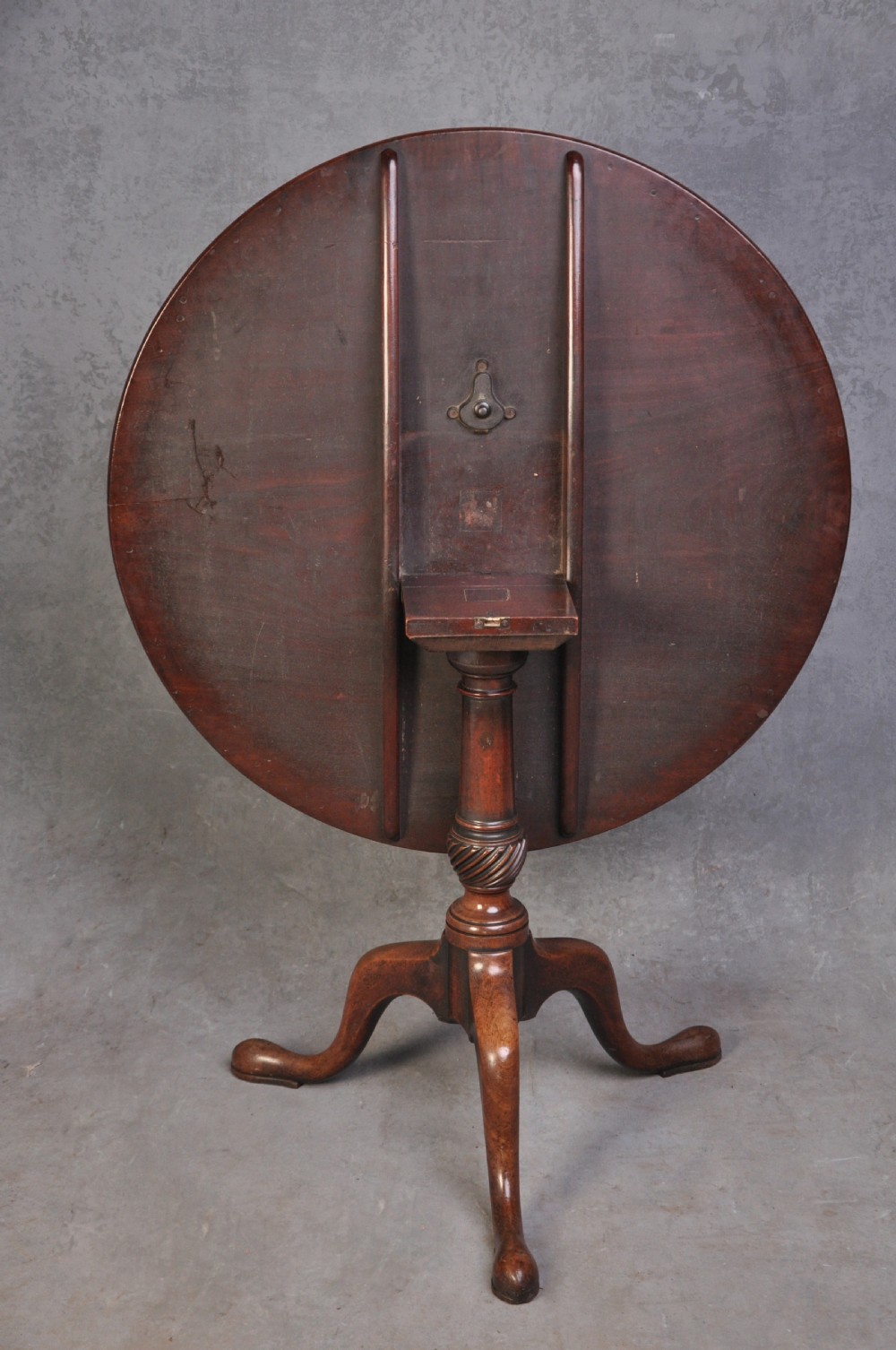 An 18th-century mahogany tripod table featuring a circular top resting on a turned column with a spiral carved knop and three cabriole legs terminating in pad feet. View V