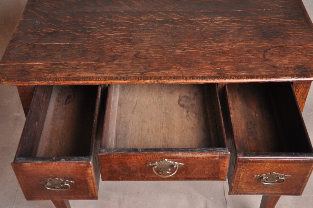 An 18th-century George I oak lowboy featuring three drawers with brass backplate handles, a shaped apron, and four cabriole legs. View IV