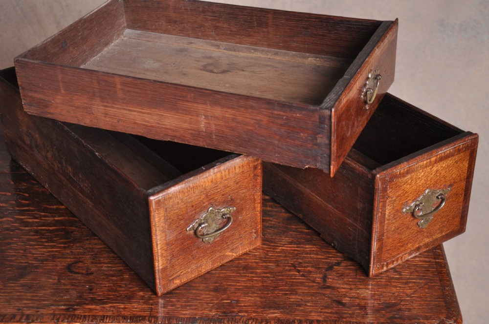 An 18th-century George I oak lowboy featuring three drawers with brass backplate handles, a shaped apron, and four cabriole legs. View V
