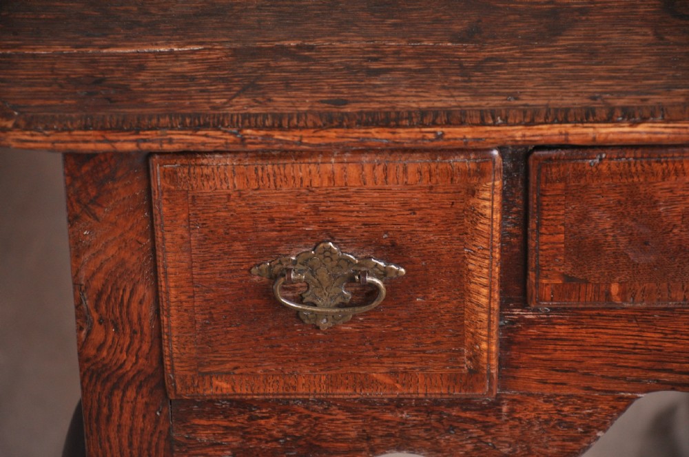 An 18th-century George I oak lowboy featuring three drawers with brass backplate handles, a shaped apron, and four cabriole legs. View VI