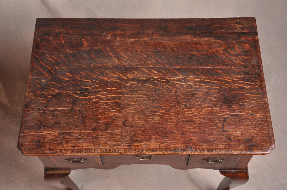 An 18th-century George I oak lowboy featuring three drawers with brass backplate handles, a shaped apron, and four cabriole legs. View VII