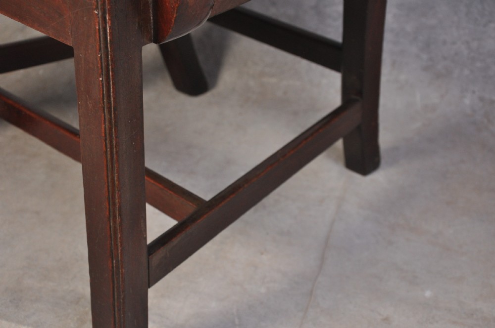 An 18th-century Hepplewhite style mahogany armchair featuring a carved pierced splat, shaped arms, square legs with stretchers, and a beige upholstered seat. View V