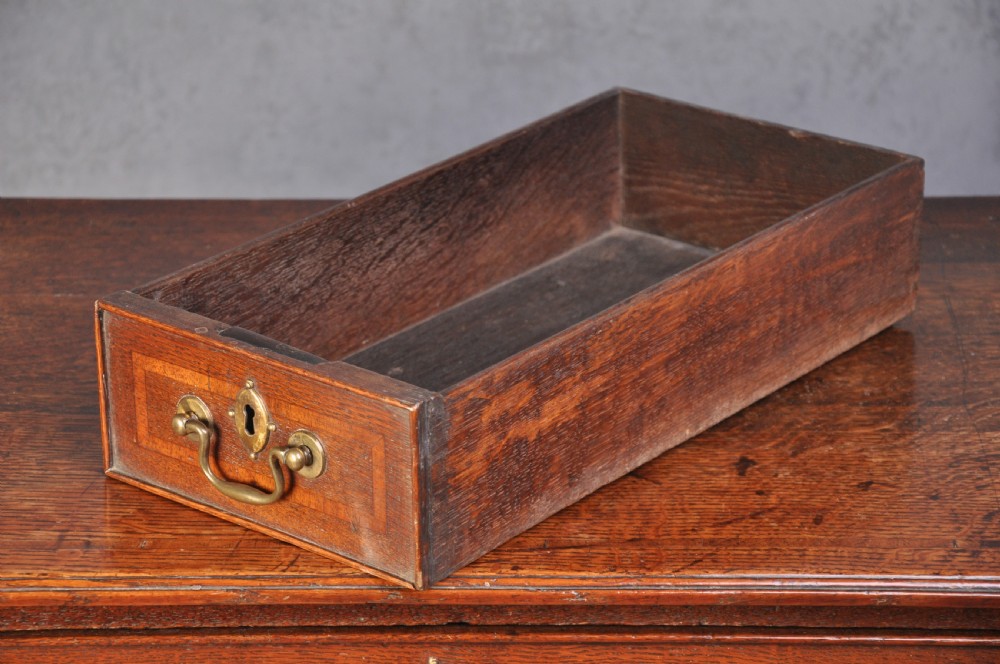 An 18th-century oak lowboy table featuring three inlaid drawers, brass swan-neck handles, an arched apron, and cabriole legs. View V