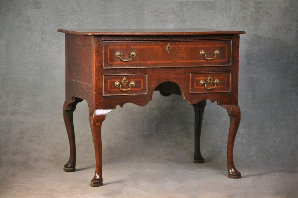 An 18th-century oak lowboy table featuring three inlaid drawers, brass swan-neck handles, an arched apron, and cabriole legs. View XI