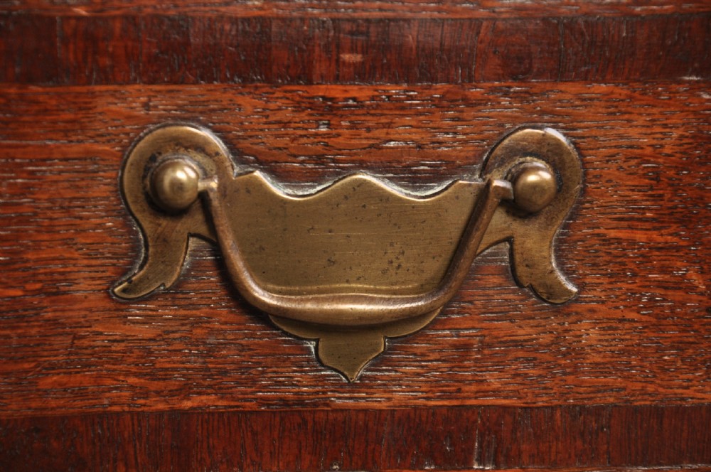 An early 18th-century oak chest on stand featuring two-part construction, multiple drawers with brass drop handles, a shaped apron, and slender cabriole legs. View II