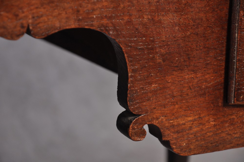 An early 18th-century oak chest on stand featuring two-part construction, multiple drawers with brass drop handles, a shaped apron, and slender cabriole legs. View IV