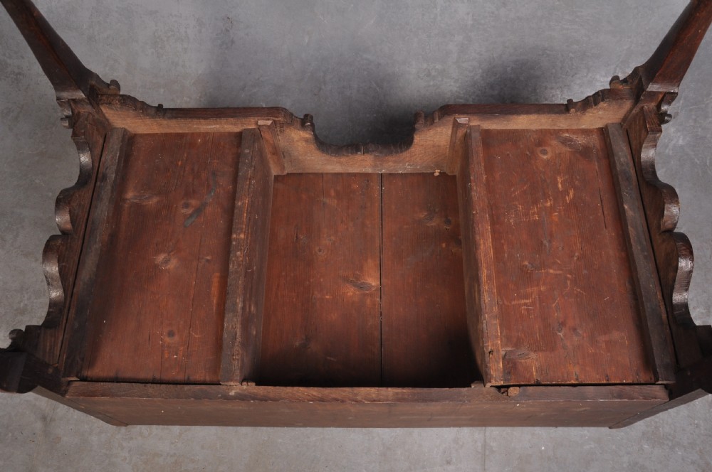 An early 18th-century oak chest on stand featuring two-part construction, multiple drawers with brass drop handles, a shaped apron, and slender cabriole legs. View XII