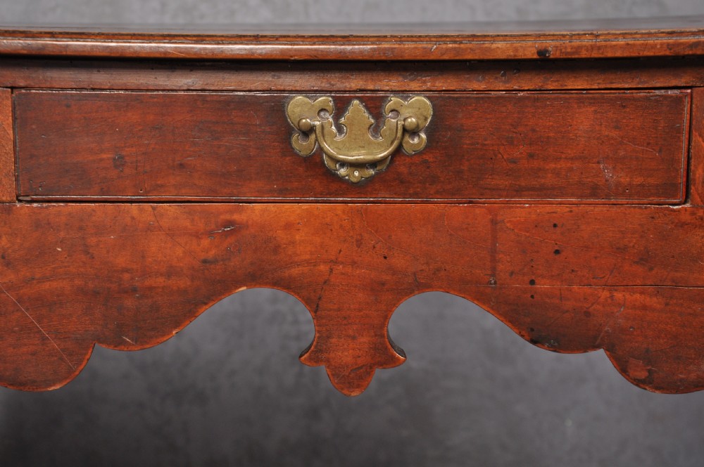 An 18th-century cherrywood lowboy featuring three drawers with brass batwing handles, a shaped apron, and cabriole legs with ball-and-claw feet. View IV