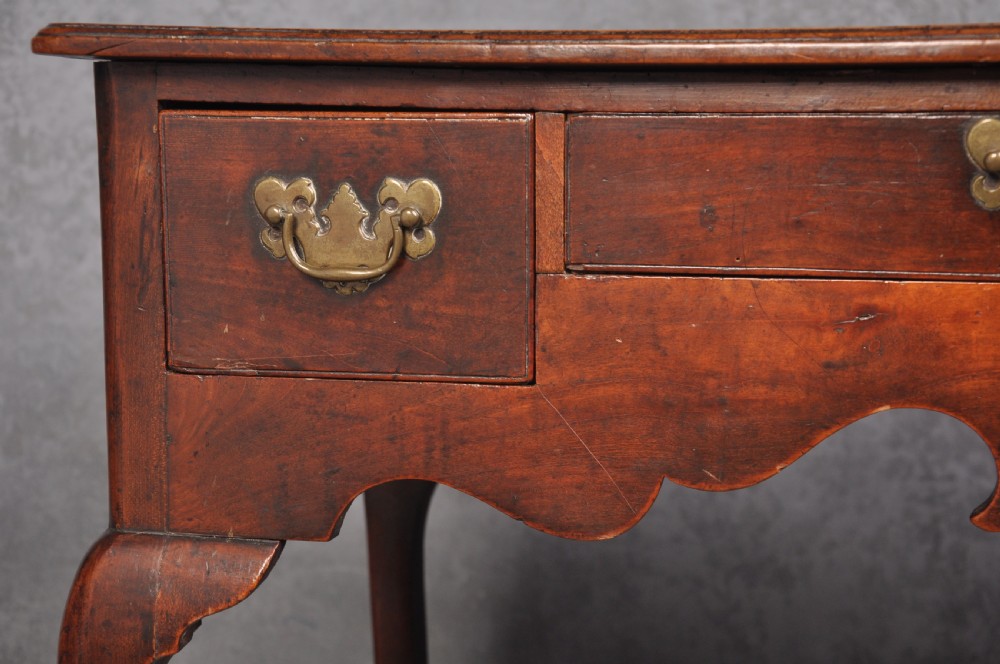 An 18th-century cherrywood lowboy featuring three drawers with brass batwing handles, a shaped apron, and cabriole legs with ball-and-claw feet. View V