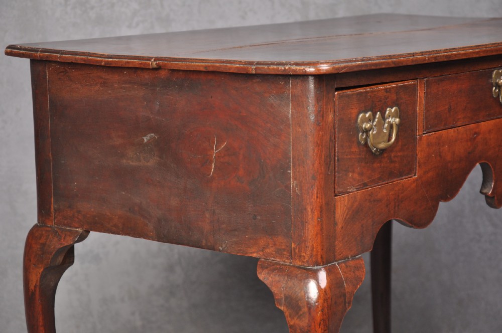 An 18th-century cherrywood lowboy featuring three drawers with brass batwing handles, a shaped apron, and cabriole legs with ball-and-claw feet. View X