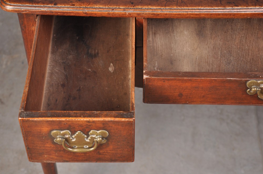 An 18th-century cherrywood lowboy featuring three drawers with brass batwing handles, a shaped apron, and cabriole legs with ball-and-claw feet. View XI