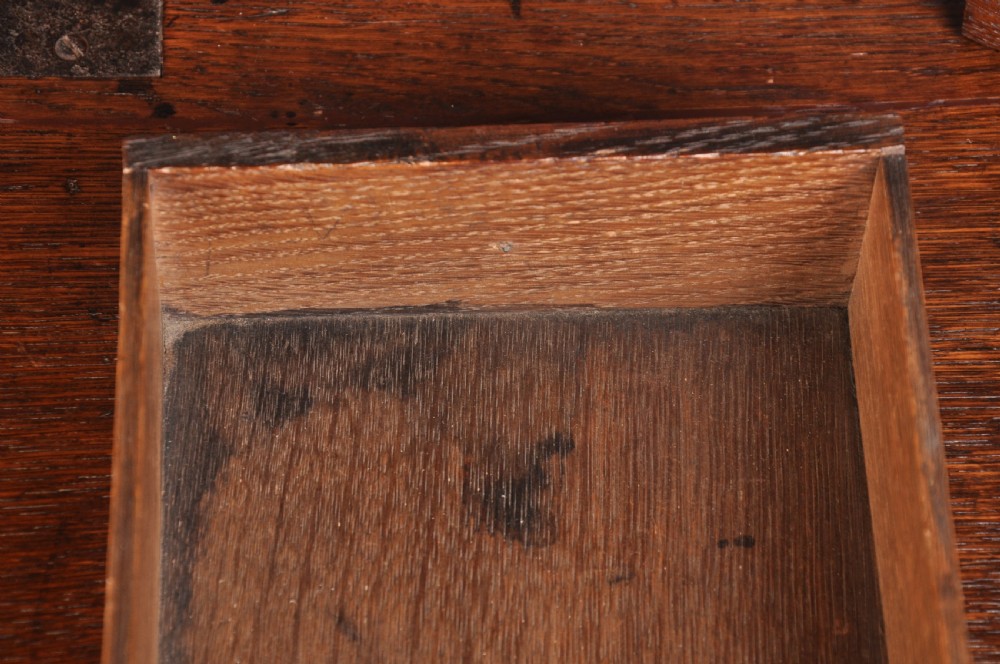 An early eighteenth-century oak bureau featuring a slanted drop-front desk above graduated drawers with brass drop handles and bracket feet. View VIII