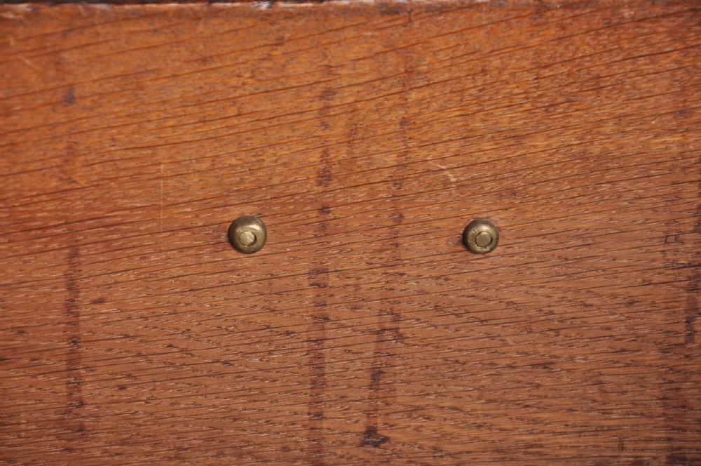 An early eighteenth-century oak bureau featuring a slanted drop-front desk above graduated drawers with brass drop handles and bracket feet. View XII