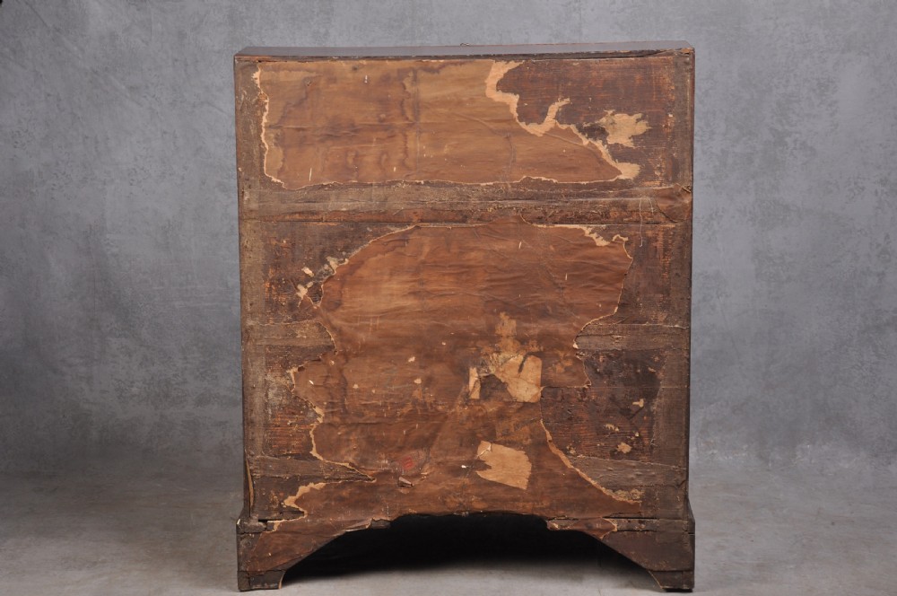 An early eighteenth-century oak bureau featuring a slanted drop-front desk above graduated drawers with brass drop handles and bracket feet. View XIII