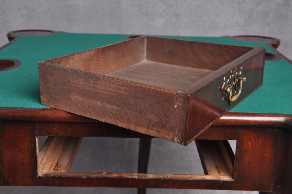 An 18th-century mahogany fold-over card table featuring slender cabriole legs, pad feet, a central drawer with a brass swing handle, and shaped corners. View IV