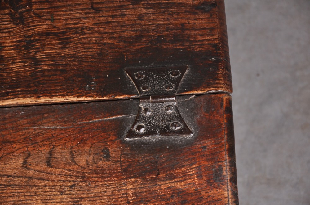 A 17th-century carved oak desk box featuring a sloped writing lid, iron hinges, iron lock plate, and hand-carved scroll motifs across the front panel. View II