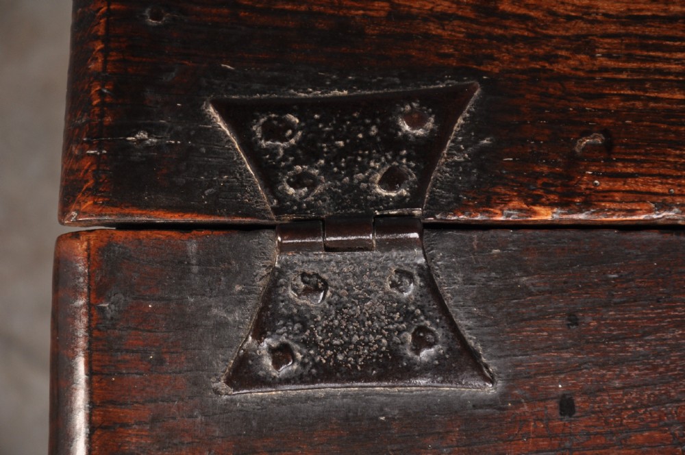 A 17th-century carved oak desk box featuring a sloped writing lid, iron hinges, iron lock plate, and hand-carved scroll motifs across the front panel. View VII