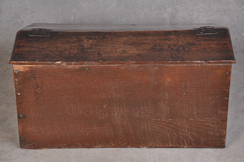 A 17th-century carved oak desk box featuring a sloped writing lid, iron hinges, iron lock plate, and hand-carved scroll motifs across the front panel. View VIII