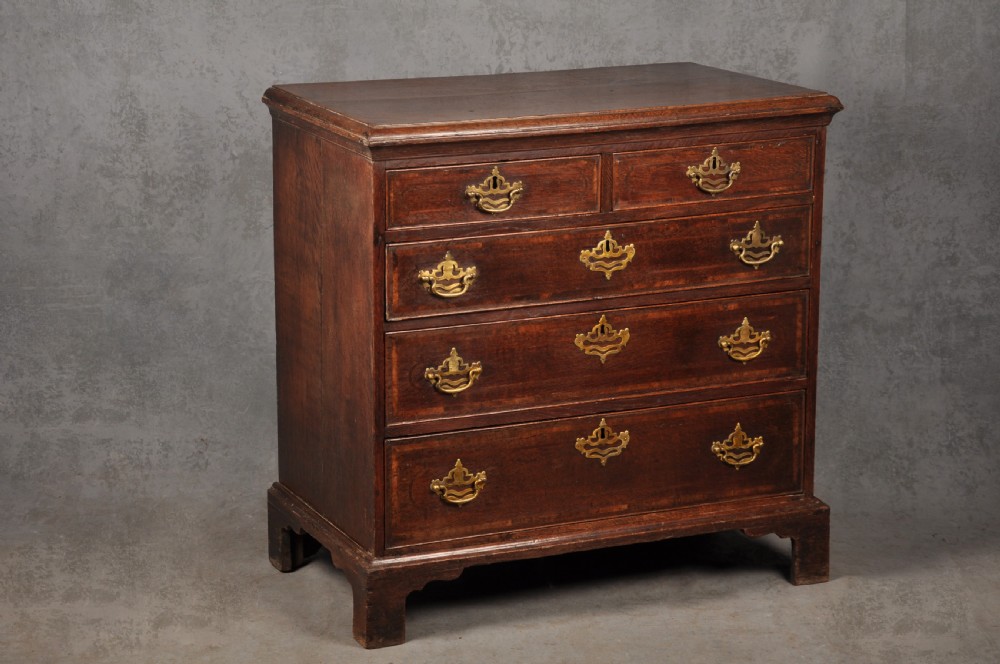 An 18th-century dark oak chest of drawers featuring inlaid drawer borders, pierced brass handles, keyhole escutcheons, and bracket feet. View III
