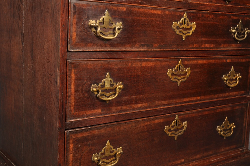 An 18th-century dark oak chest of drawers featuring inlaid drawer borders, pierced brass handles, keyhole escutcheons, and bracket feet. View IV