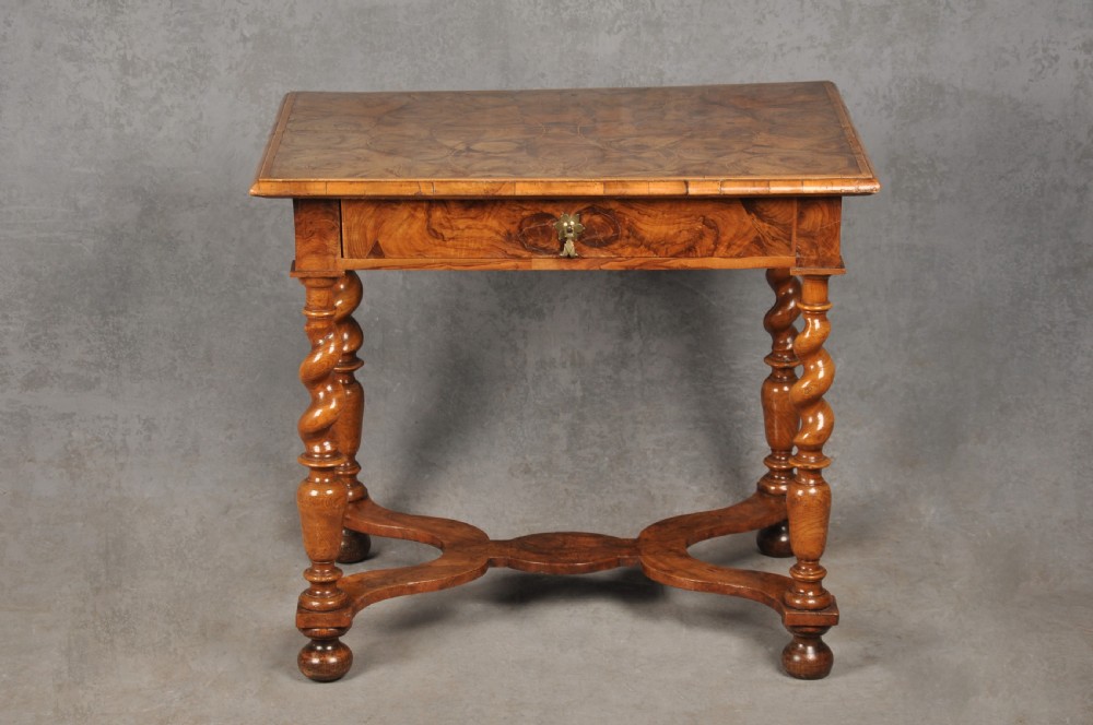 An antique olive wood side table featuring geometric oyster veneering on top, a single drawer with a brass drop handle, four barley twist legs, and a curved stretcher base. View II