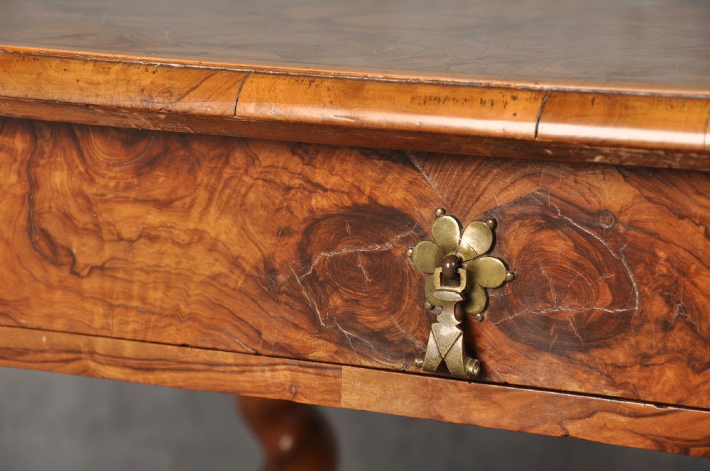 An antique olive wood side table featuring geometric oyster veneering on top, a single drawer with a brass drop handle, four barley twist legs, and a curved stretcher base. View VI