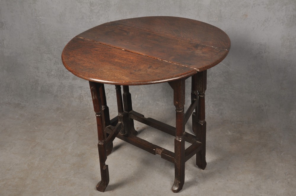 A small dark brown Queen Anne oak gateleg table shown with both drop leaves lowered, featuring turned legs and a stretcher base. View II