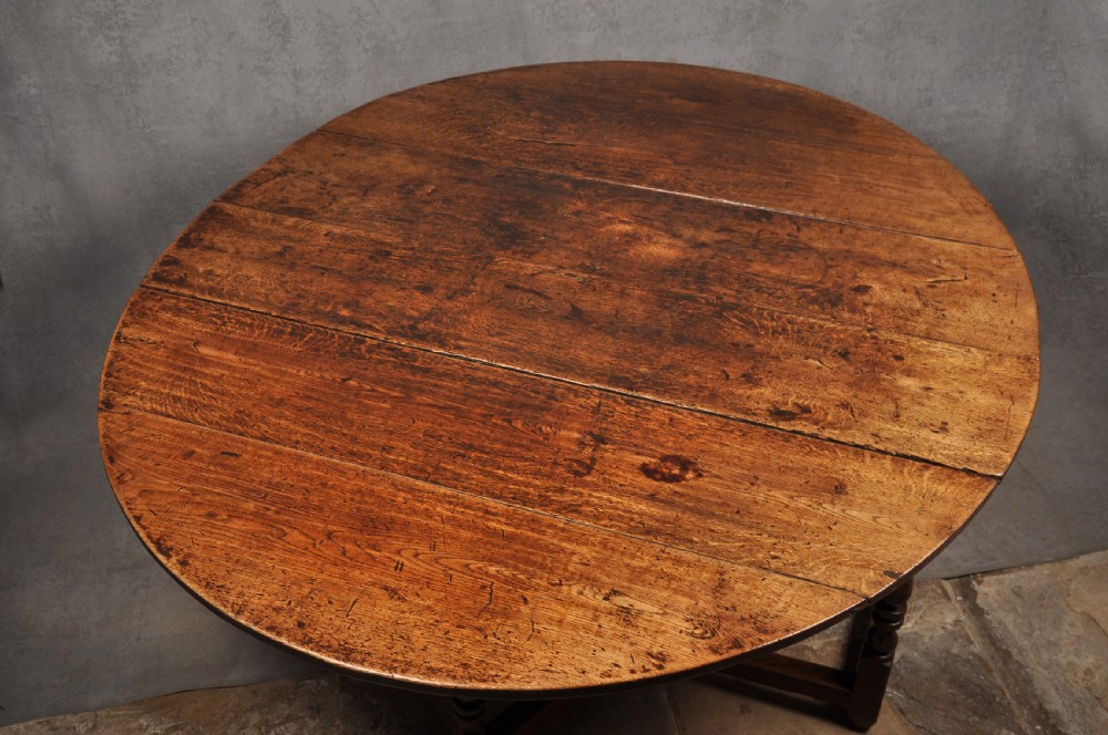 A large 17th-century solid oak gateleg dining table with two drop leaves, turned legs, and square box stretchers. View II