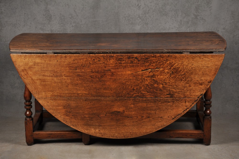 A large 17th-century solid oak gateleg dining table with two drop leaves, turned legs, and square box stretchers. View III