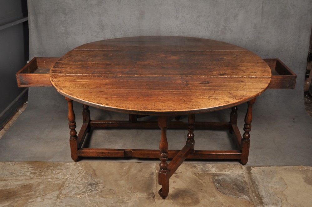 A large 17th-century solid oak gateleg dining table with two drop leaves, turned legs, and square box stretchers. View V