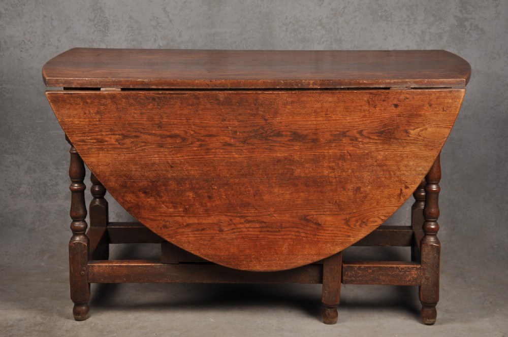 A seventeenth-century oak gateleg dining table featuring hinged drop leaves and turned wood legs with low stretchers.