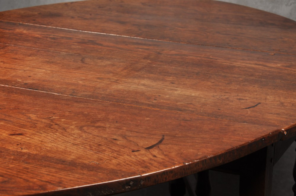 A seventeenth-century oak gateleg dining table featuring hinged drop leaves and turned wood legs with low stretchers. View II